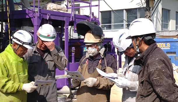 現場で打ち合わせをする作業員たち